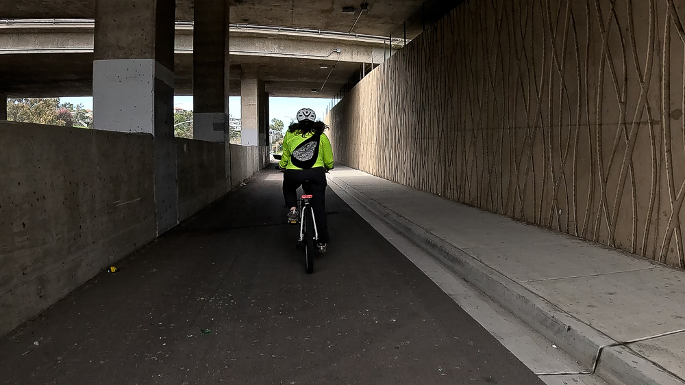 Cyclist rides under Interstate 5 in a separated bikeway on Encinitas Blvd. in Encinitas, California