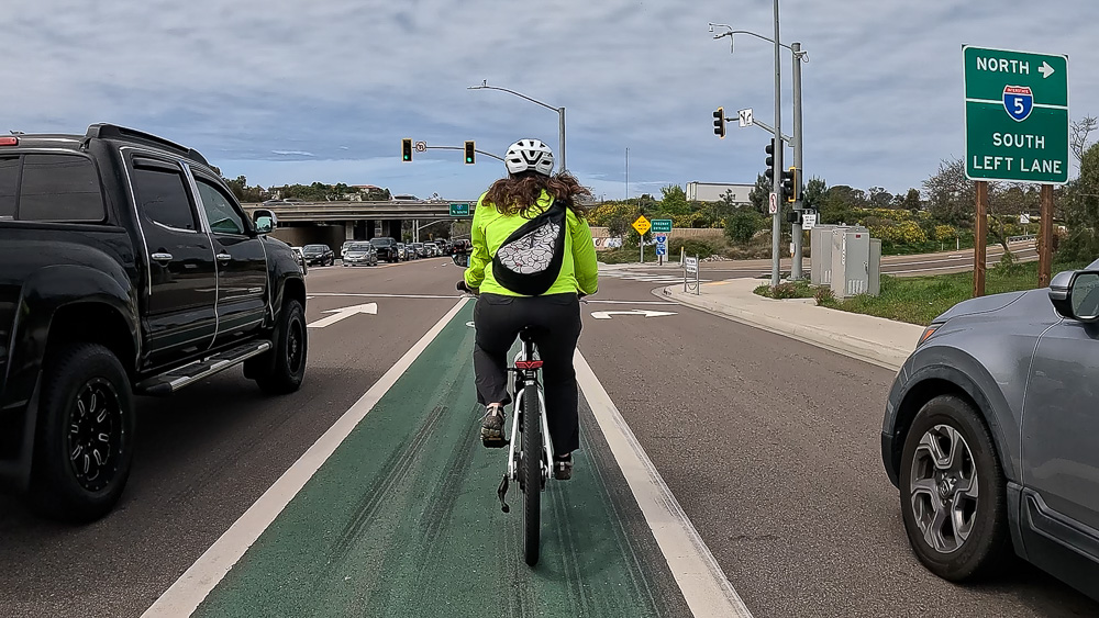 Cyclist rides between lanes of traffic on a Class II bike lane on Encinitas Blvd. near the Interstate 5 intersection in Encinitas, California