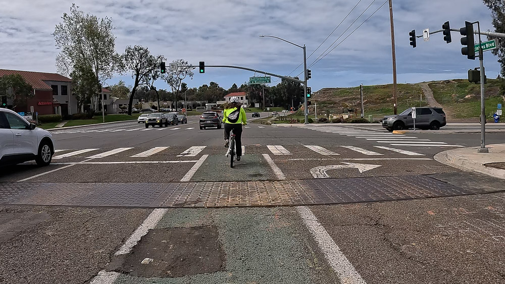 Cyclist riding westbound over construction debris in Class II bike lane on Encinitas Blvd and Quail Gardens Drive in Encinitas, California